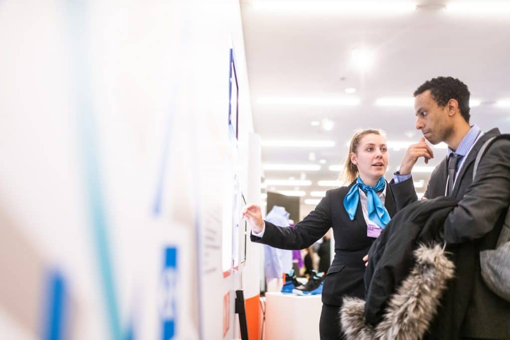 Networking is one of the things graduates must know before a job search. (A company's representative talking to a young man in a fair.